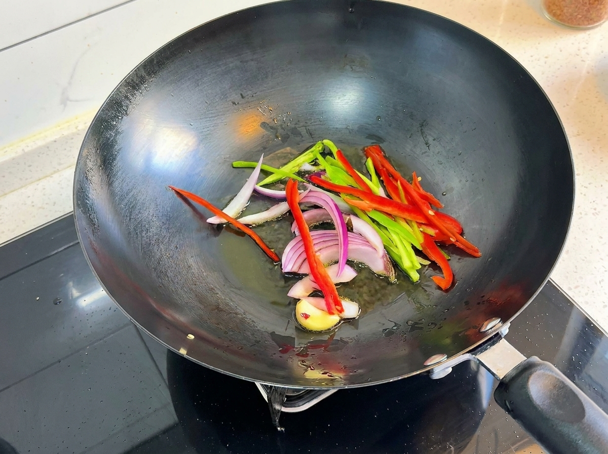 Geschnittene Paprika, Zwiebeln und Knoblauch brutzeln in einem heißen Wok.