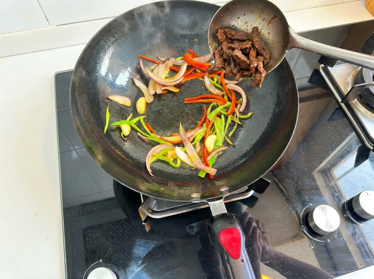 Angebratenes Fleisch wird wieder zum Gemüse in den Wok gegeben.