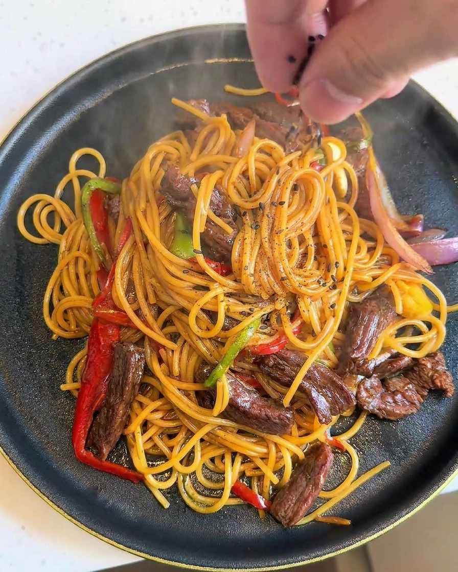 Schwarzer Sesam wird über das fertig angerichtete Pastagericht gestreut.