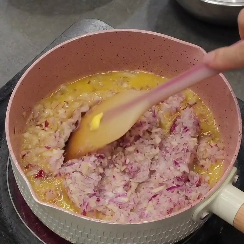 Gehackte Zwiebeln und Knoblauch werden in Butter in einem kleinen Topf angedünstet.
