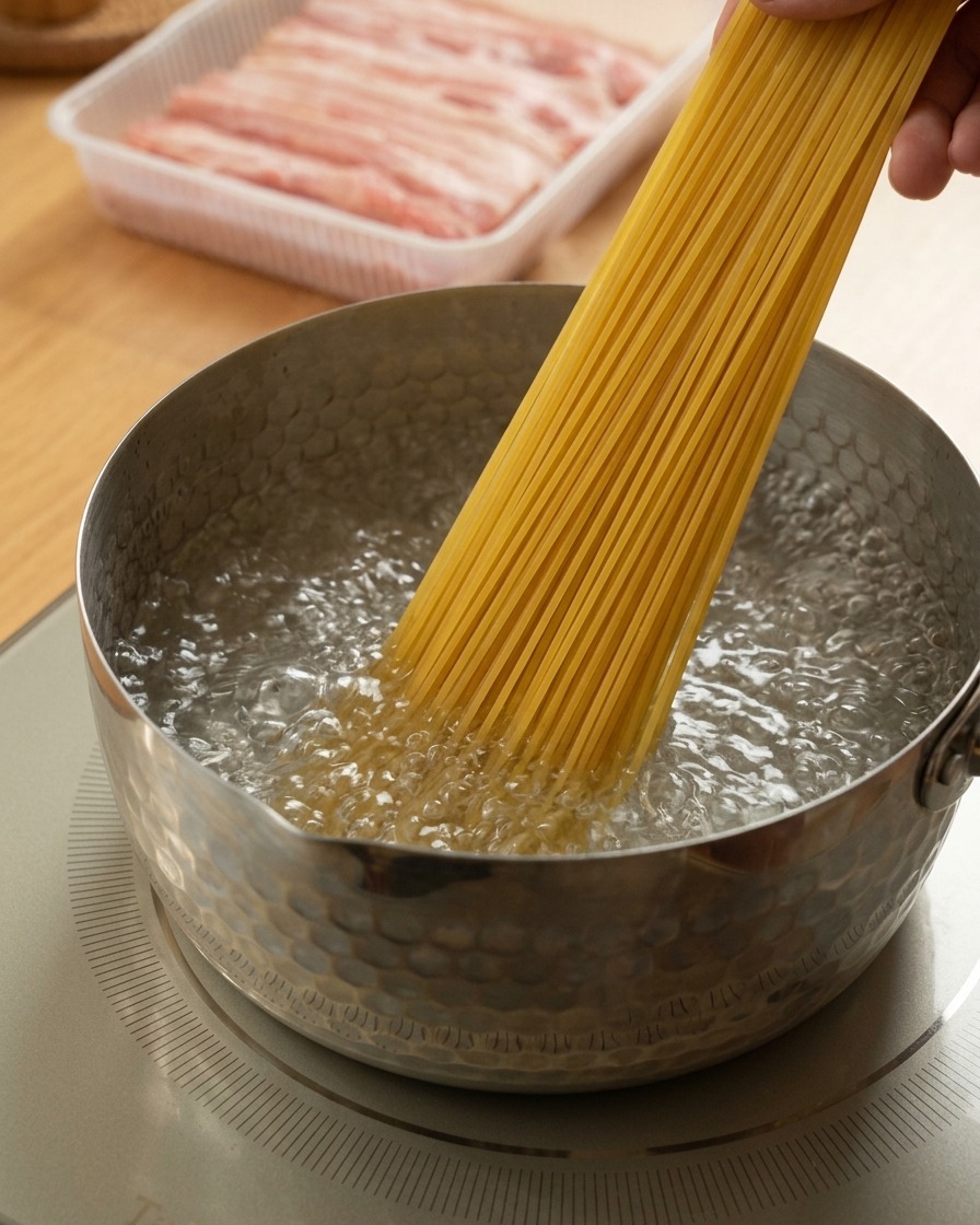 Eine Hand gibt ein Bündel Spaghetti in sprudelnd kochendes Wasser.