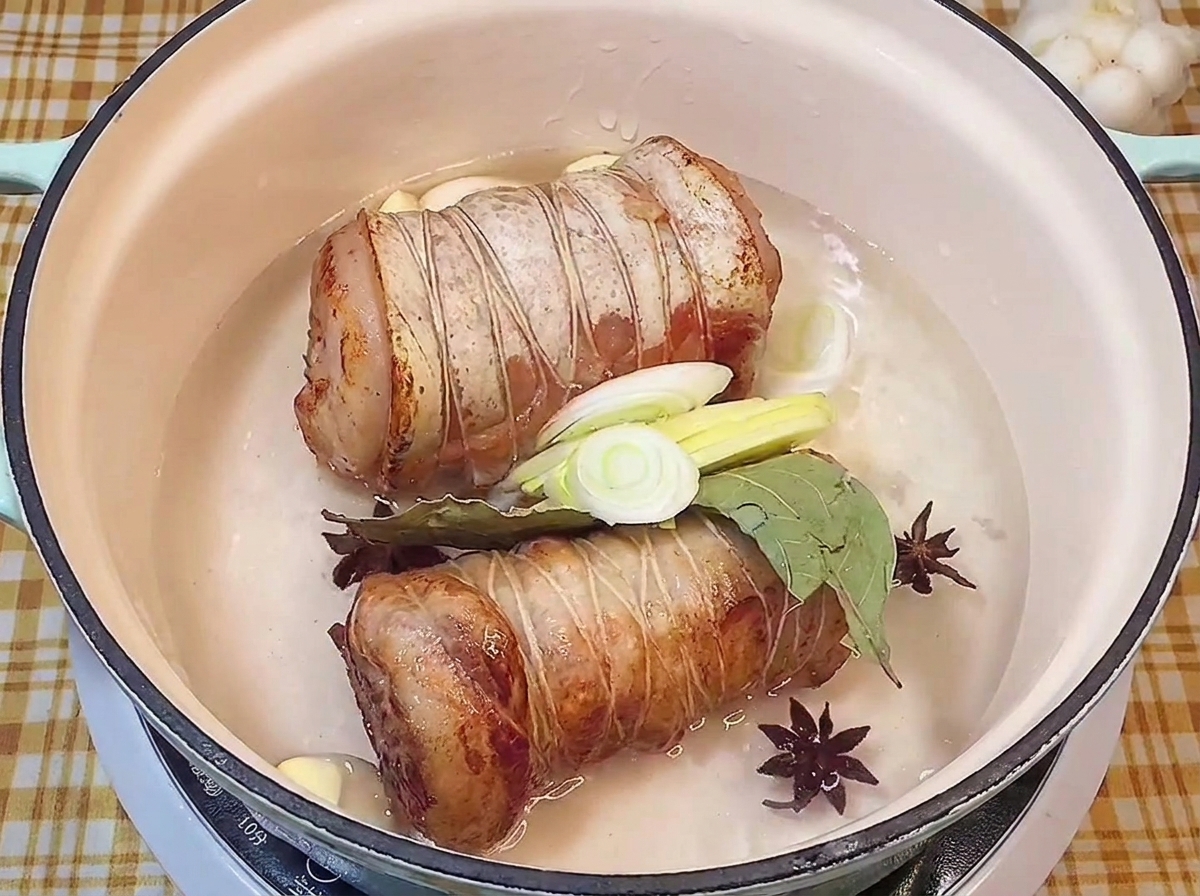Angebratene Rollen in einem Topf mit Sternanis, Lorbeer, Knoblauch und Lauch.