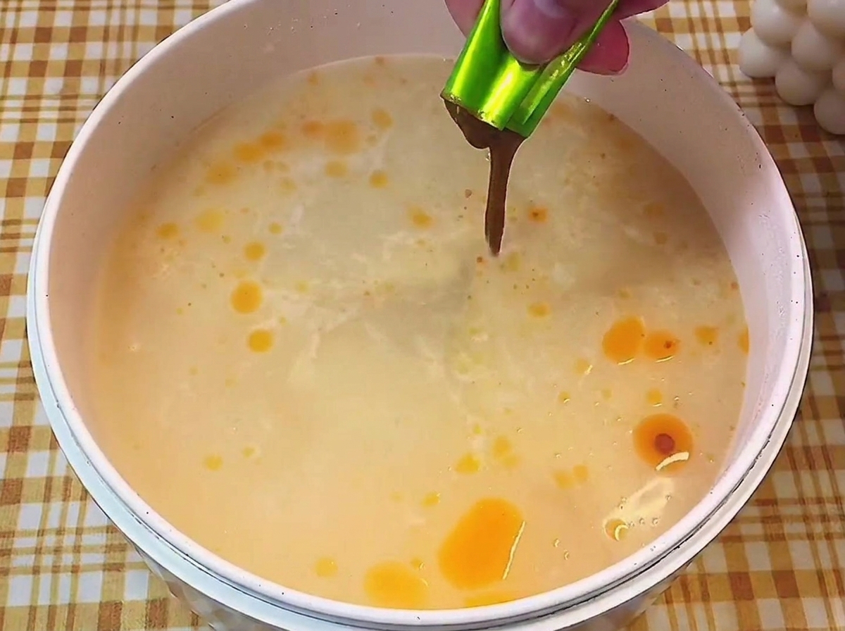 Eine Hand drückt flüssige Würze aus einem Beutel in kochendes Wasser.