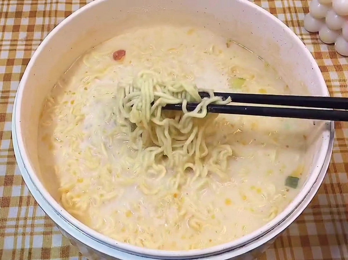 Stäbchen heben gewellte Ramen-Nudeln aus der cremigen Suppe.