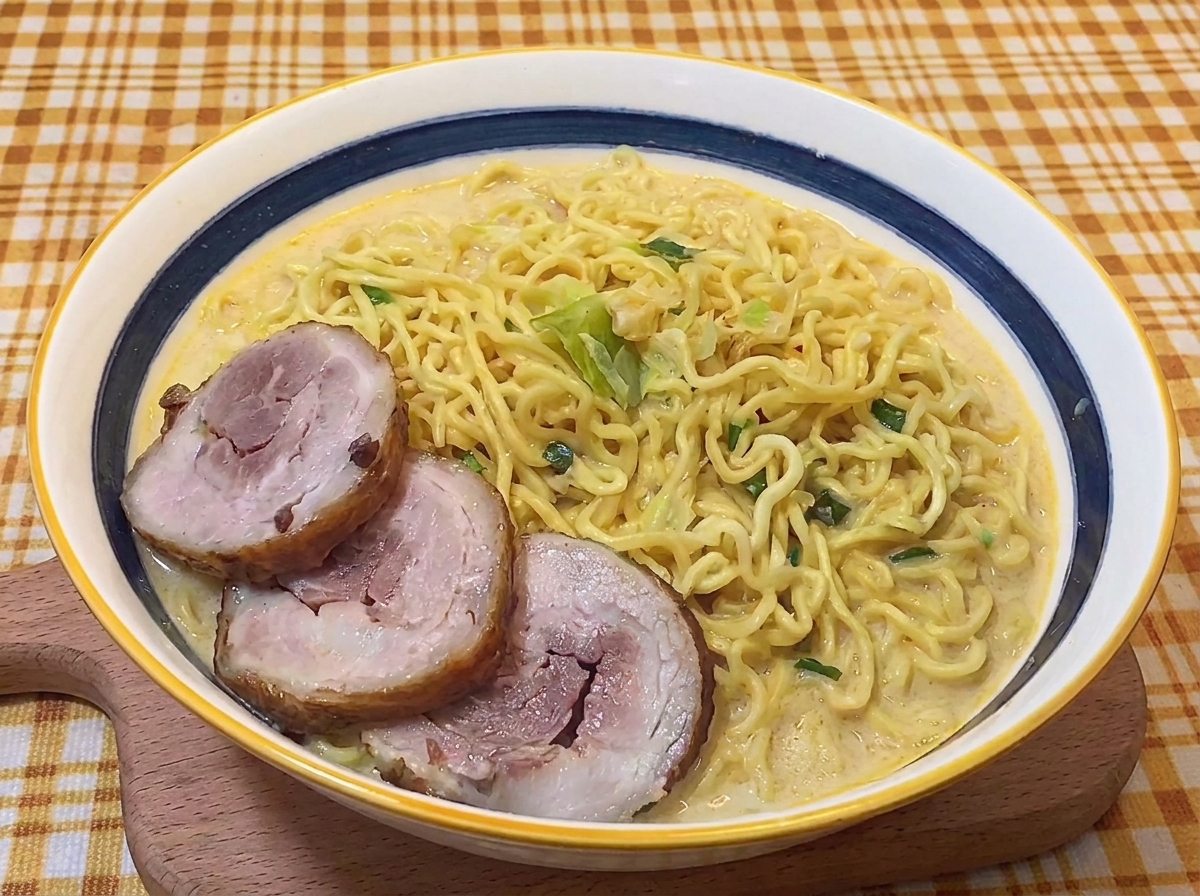 Drei Scheiben Chashu liegen auf den Nudeln in der cremigen Brühe.