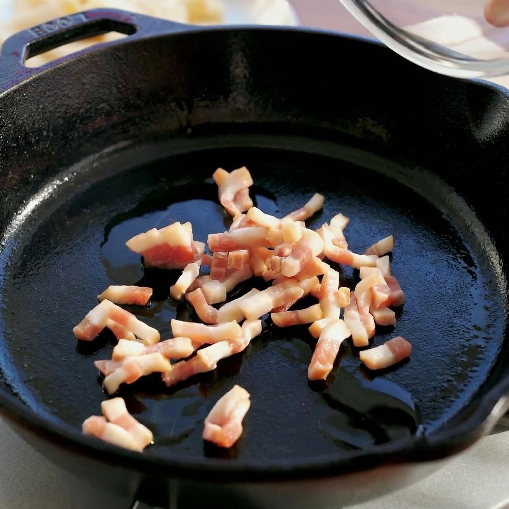 Rohe Guanciale-Würfel werden aus einer Schüssel in eine dunkle gusseiserne Pfanne geschüttet.