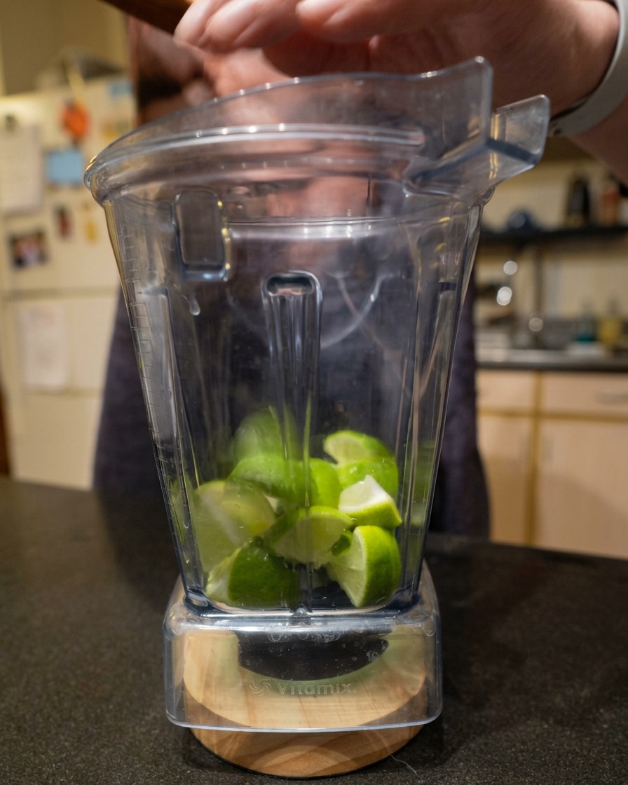 Frisch geviertelte Limetten in einem durchsichtigen Vitamix-Mixer-Behälter.