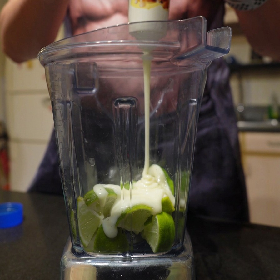 Dicke gezuckerte Kondensmilch wird aus einer Tube über frisch gehackte Limetten in einem Mixer gepresst.