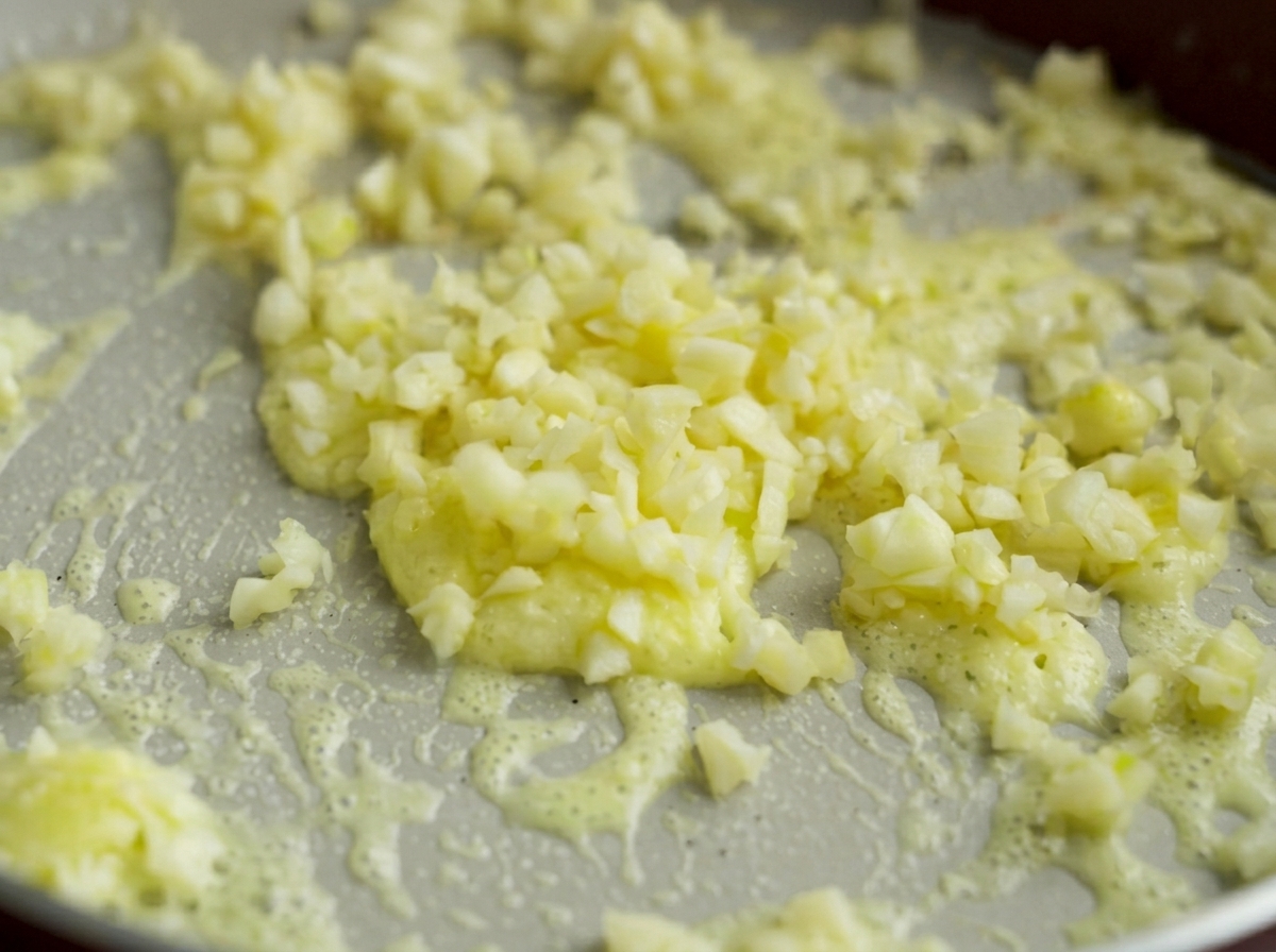 Fein gehackter Knoblauch dünstet in der Butter-Stärke-Mischung in der Pfanne.