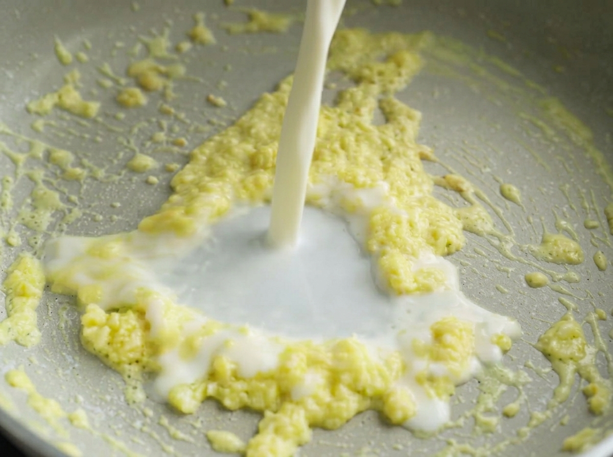 Milch wird in die Pfanne zur Knoblauch-Butter-Mischung gegossen.