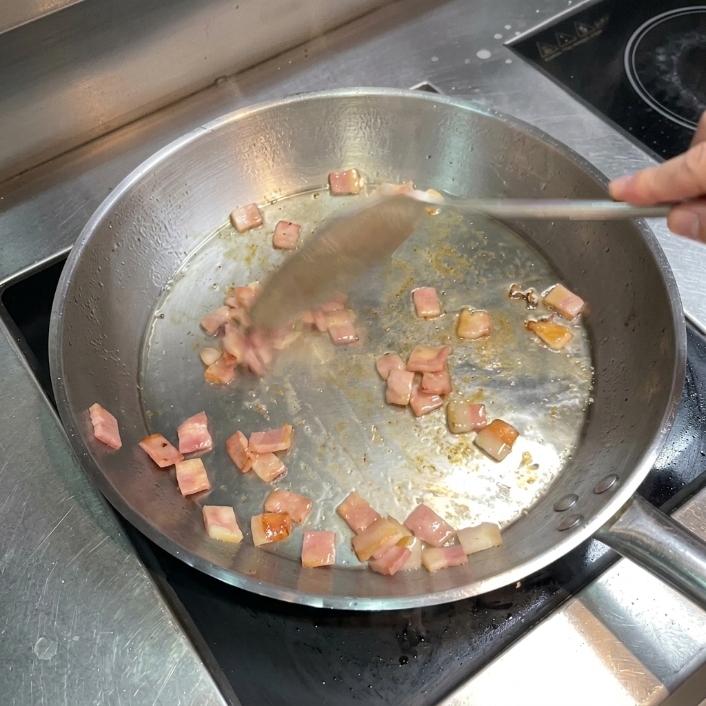 Ein Pfannenwender rührt gebräunten, knusprigen Speck in der Pfanne um.