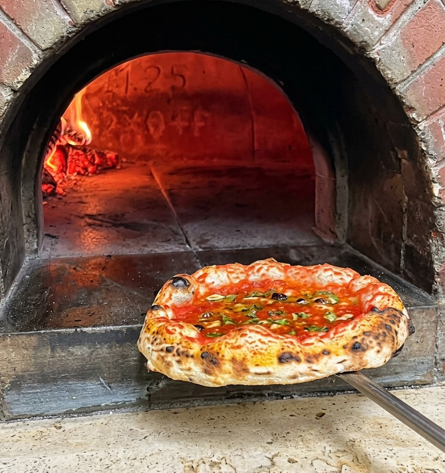 Eine frisch gebackene neapolitanische Pizza mit dunklen Punkten am Rand wird auf einem Schieber aus dem Ofen geholt.