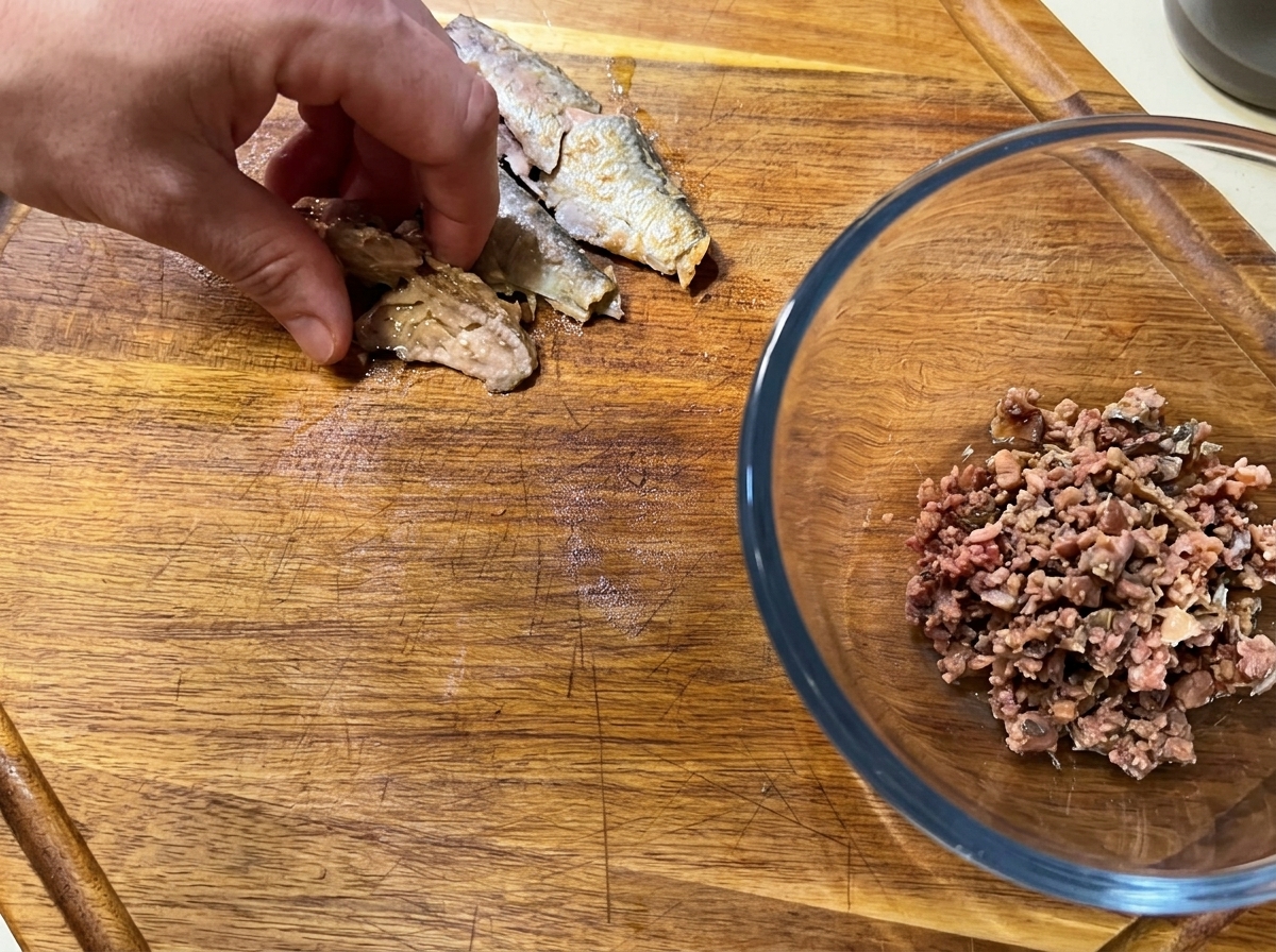 Sardinenfilets werden auf einem Schneidebrett zerkleinert.
