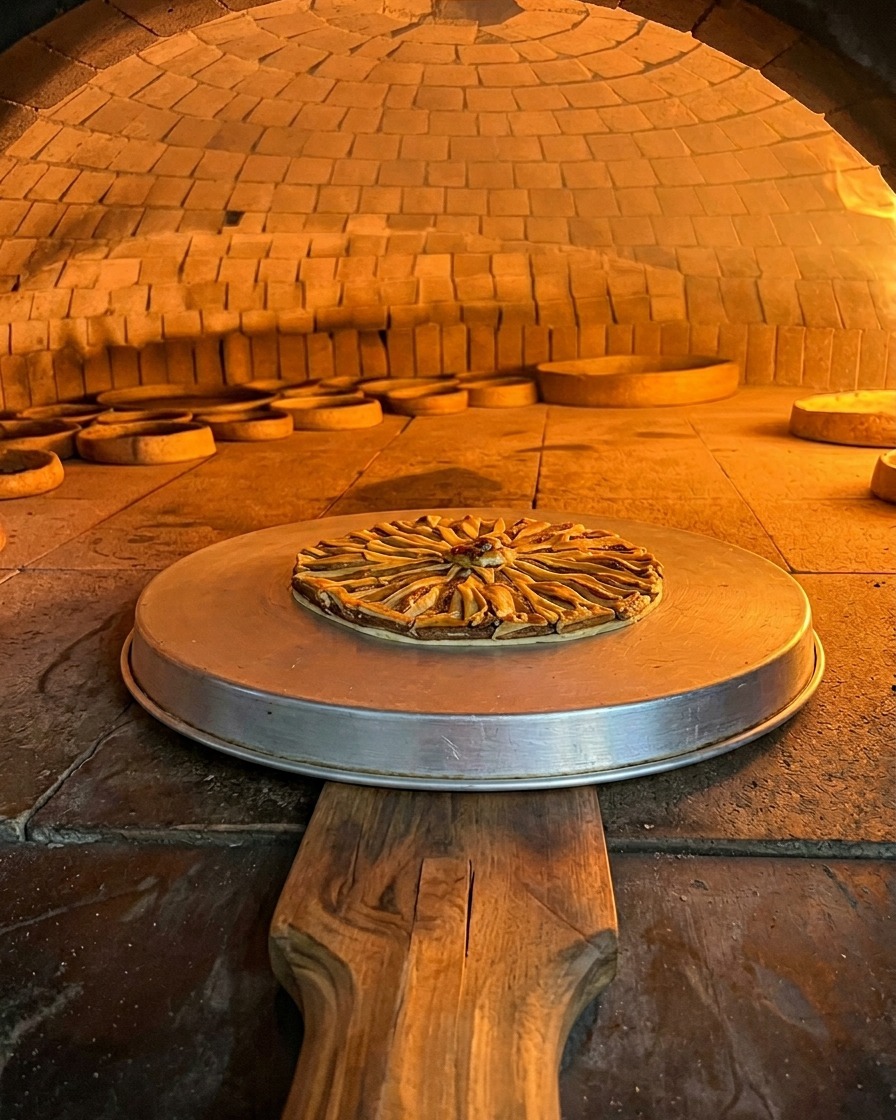Die Sardellen-Pizza backt auf einem Metallblech in der glühenden Kammer eines Holzofens.