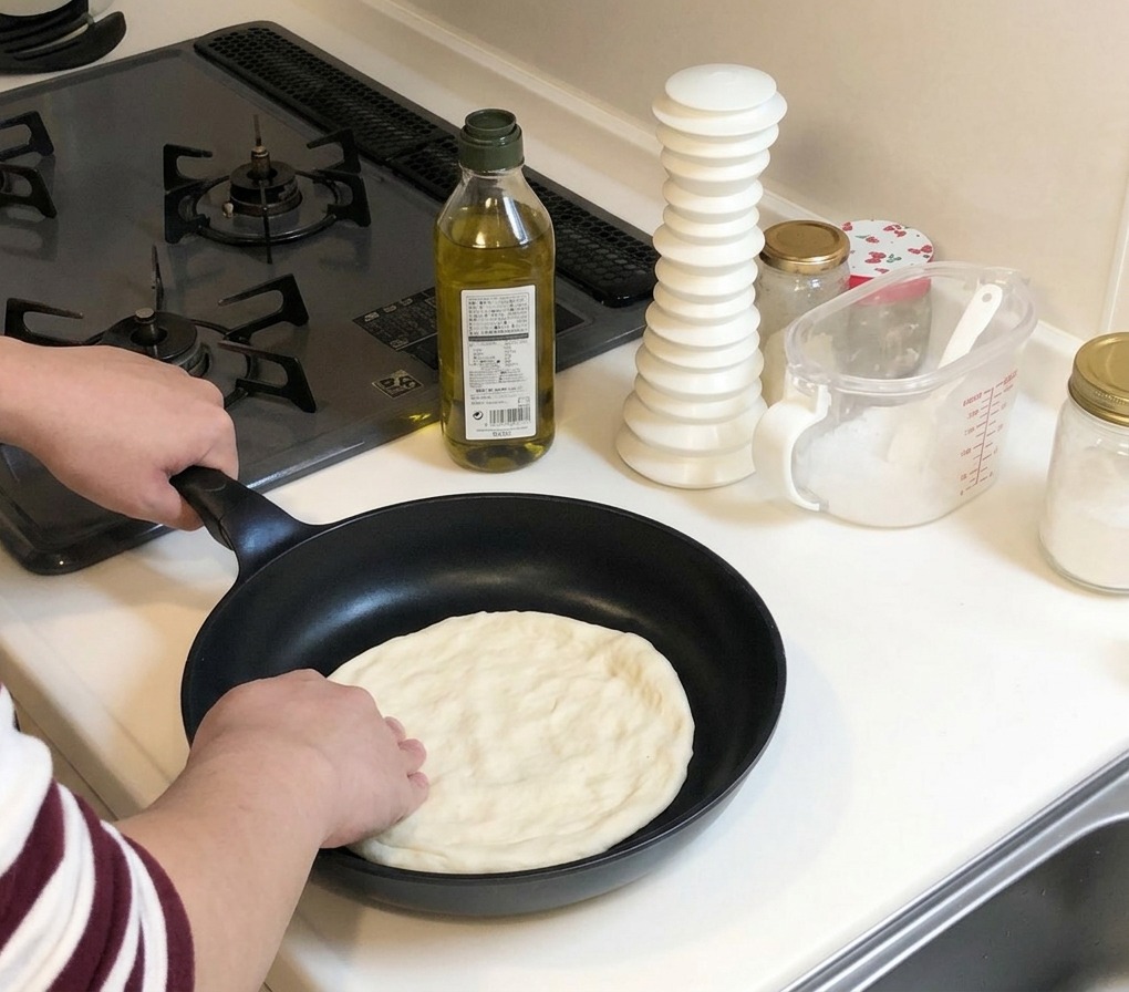 Hände drücken den Pizzateig bis an die Ränder einer kalten Bratpfanne aus.