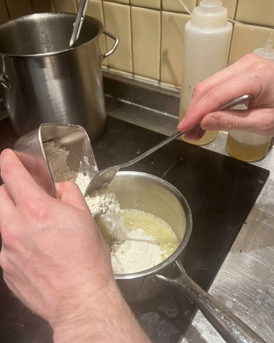Mehl wird in die Butter-Schalotten-Mischung gegeben, um eine Roux herzustellen.