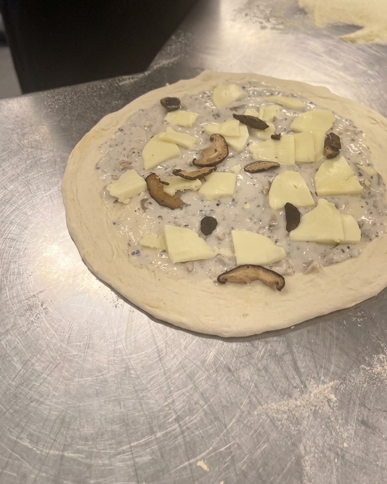 Gebratene Shiitake- und Champignonscheiben werden über dem Mozzarella verteilt.