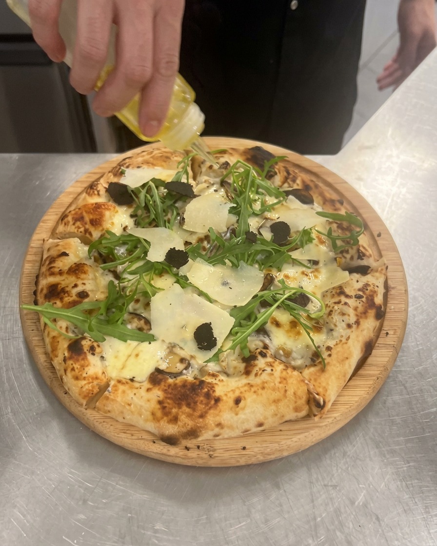 Trüffelöl wird als letzter Schliff über die fertige Pizza geträufelt.