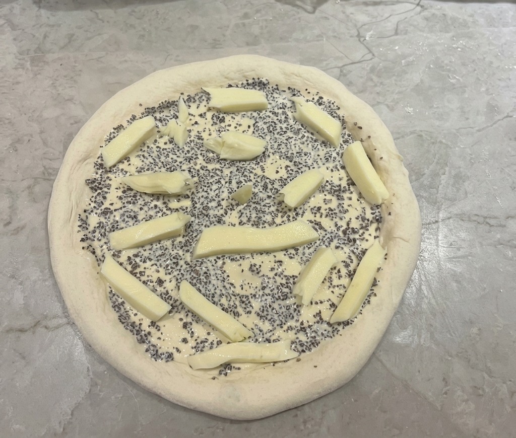 Pizzateig mit Trüffelsauce und darauf verteilten Mozzarella-Stiften.