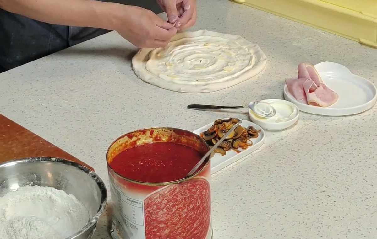 Hände legen orangefarbene Cordyceps-Blüten auf die Pizza.