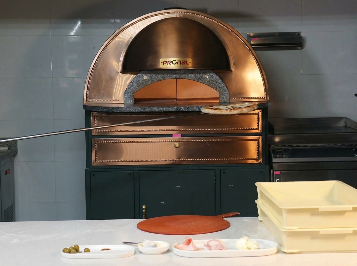 Eine fertig gebackene Pizza mit Blasen am Rand wird aus dem Ofen geholt.