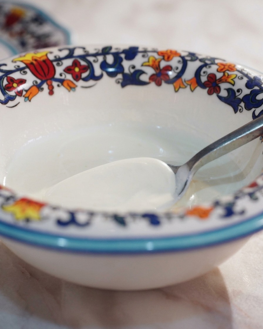 Ein Löffel Sahne in einer kleinen Schale wird mit schwarzer Trüffelpaste zu einer gleichmäßigen Creme vermengt.