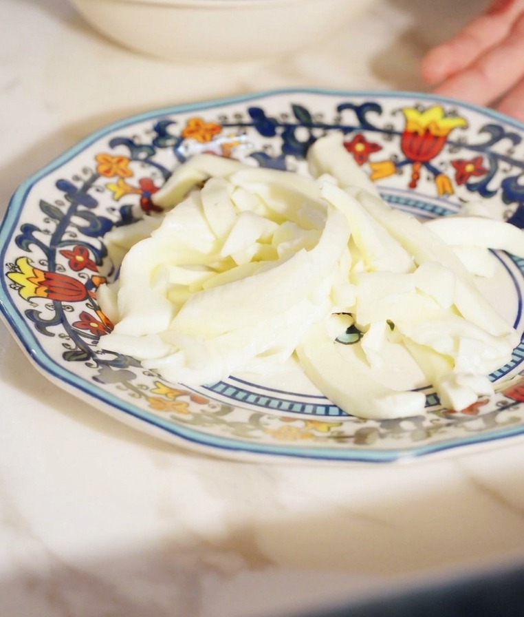 Gleichmäßige Streifen von weißem Fior di Latte Käse auf einem kleinen Teller.