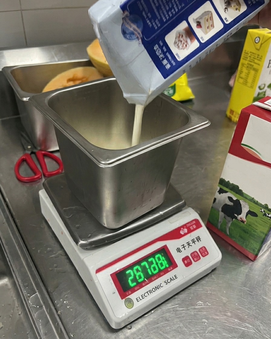 Milch wird aus einer Packung in einen Messbehälter auf einer Digitalwaage gegossen.