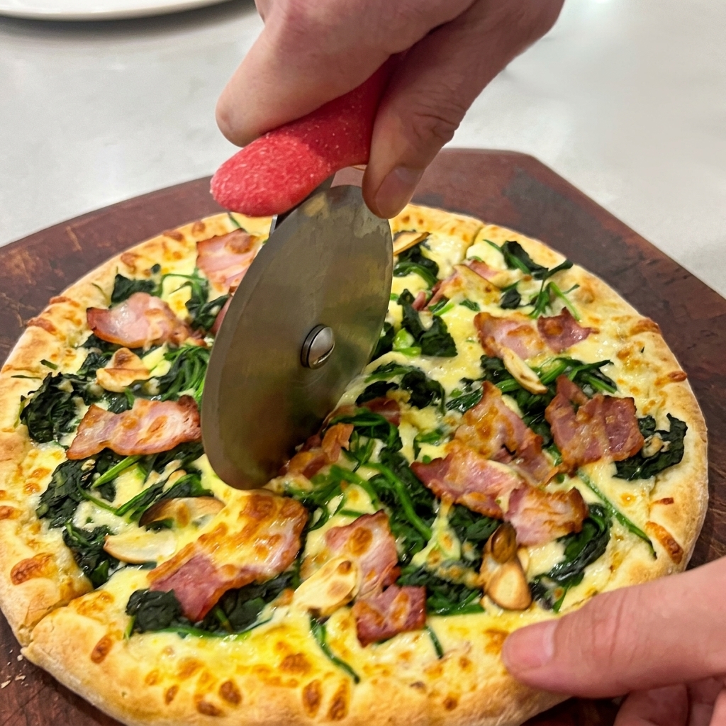 Hände schneiden die heiße Pizza mit einem Pizzaroller auf einem Holzbrett in Stücke.