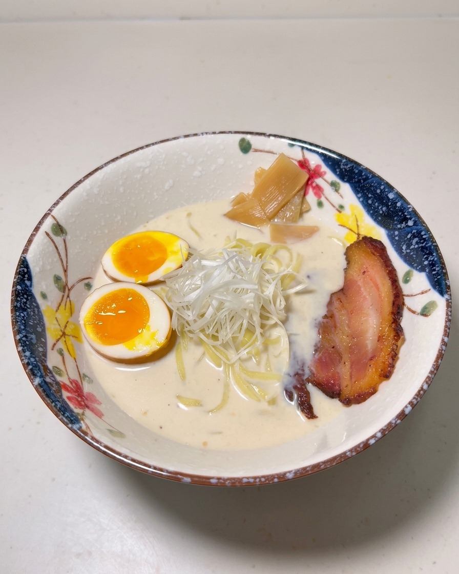 Eine Ramen-Schüssel garniert mit Ei, Bambussprossen, Frühlingszwiebeln und einer Scheibe gebratenem Chashu.
