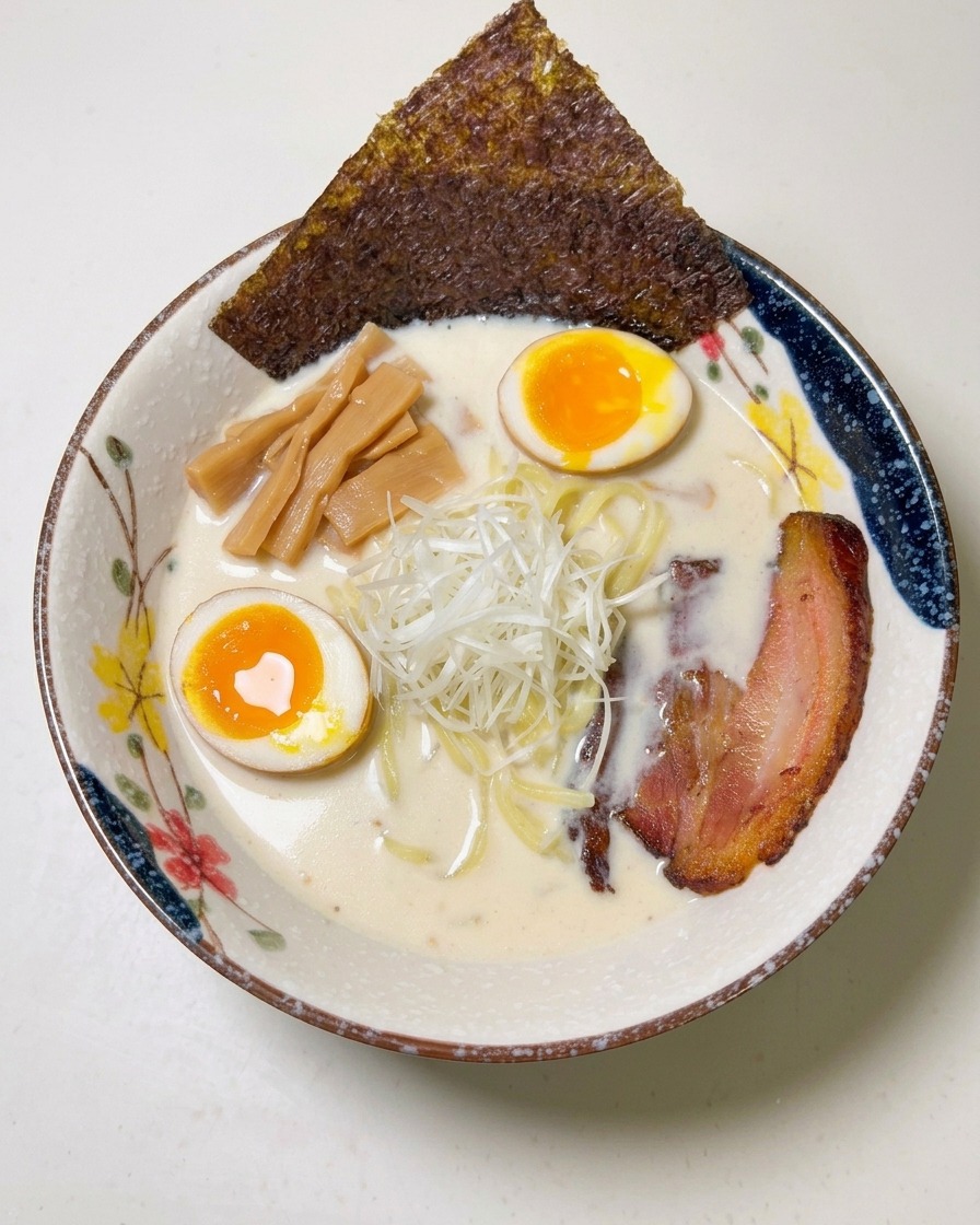 Ein Blatt dunkle Nori-Alge wird am Rand der gefüllten Ramen-Schüssel platziert.