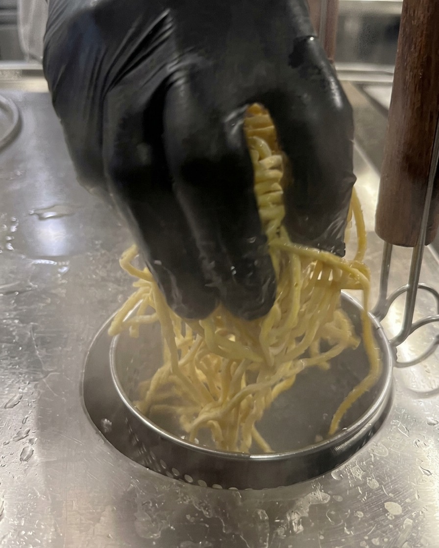 Gelbe Nudeln werden in einen Topf mit kochendem Wasser gegeben.