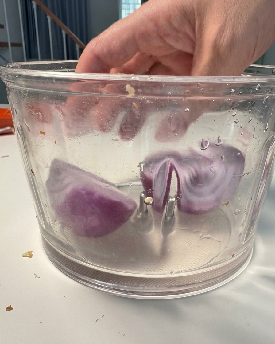 Rote Zwiebelstücke im Mixer bereit zum Zerkleinern.