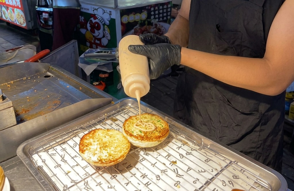 Orangefarbene Burgersauce wird aus einer Flasche auf die gerösteten Brötchenhälften gespritzt.
