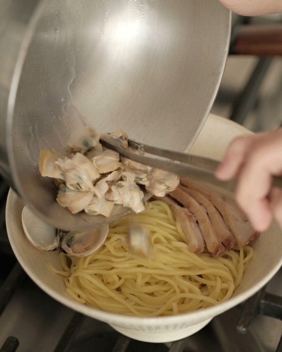 Geöffnete Muscheln werden auf die vorbereitete Ramen-Schüssel mit Ente und Ei gegeben.