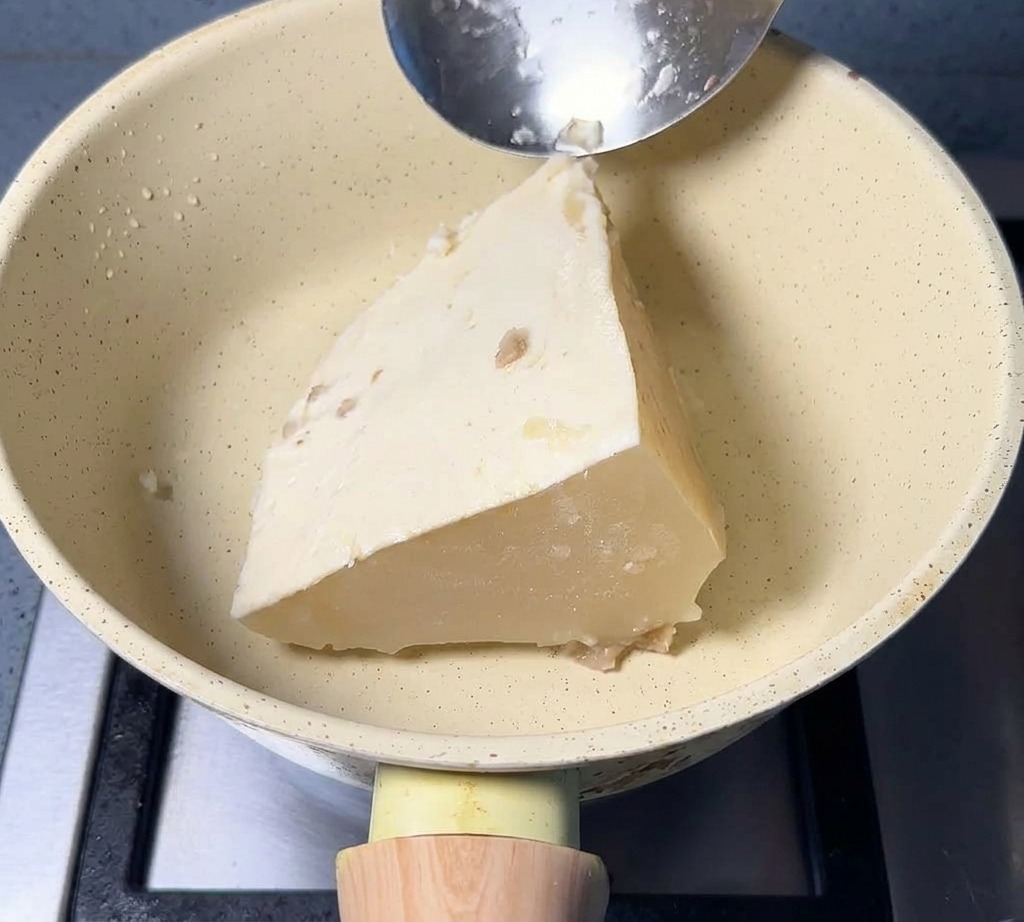 Ein gefrorener Block weißer Schweinebrühe liegt in einem Topf neben Fischpulver.