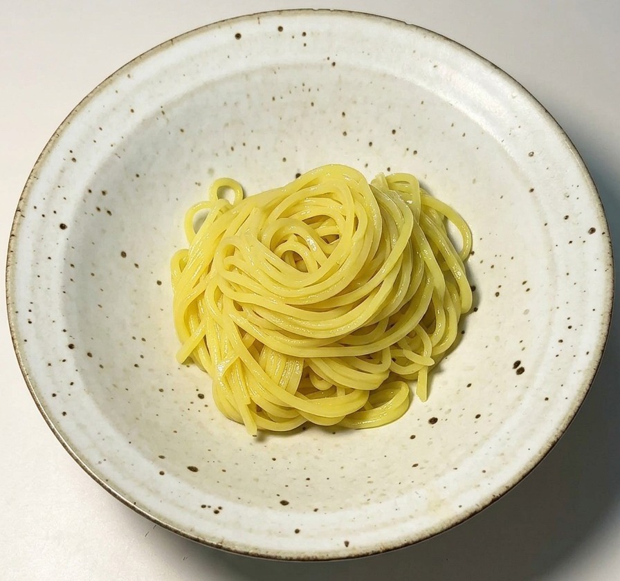 Ein Nest aus gelben Ramen-Nudeln in einer weißen Schale.