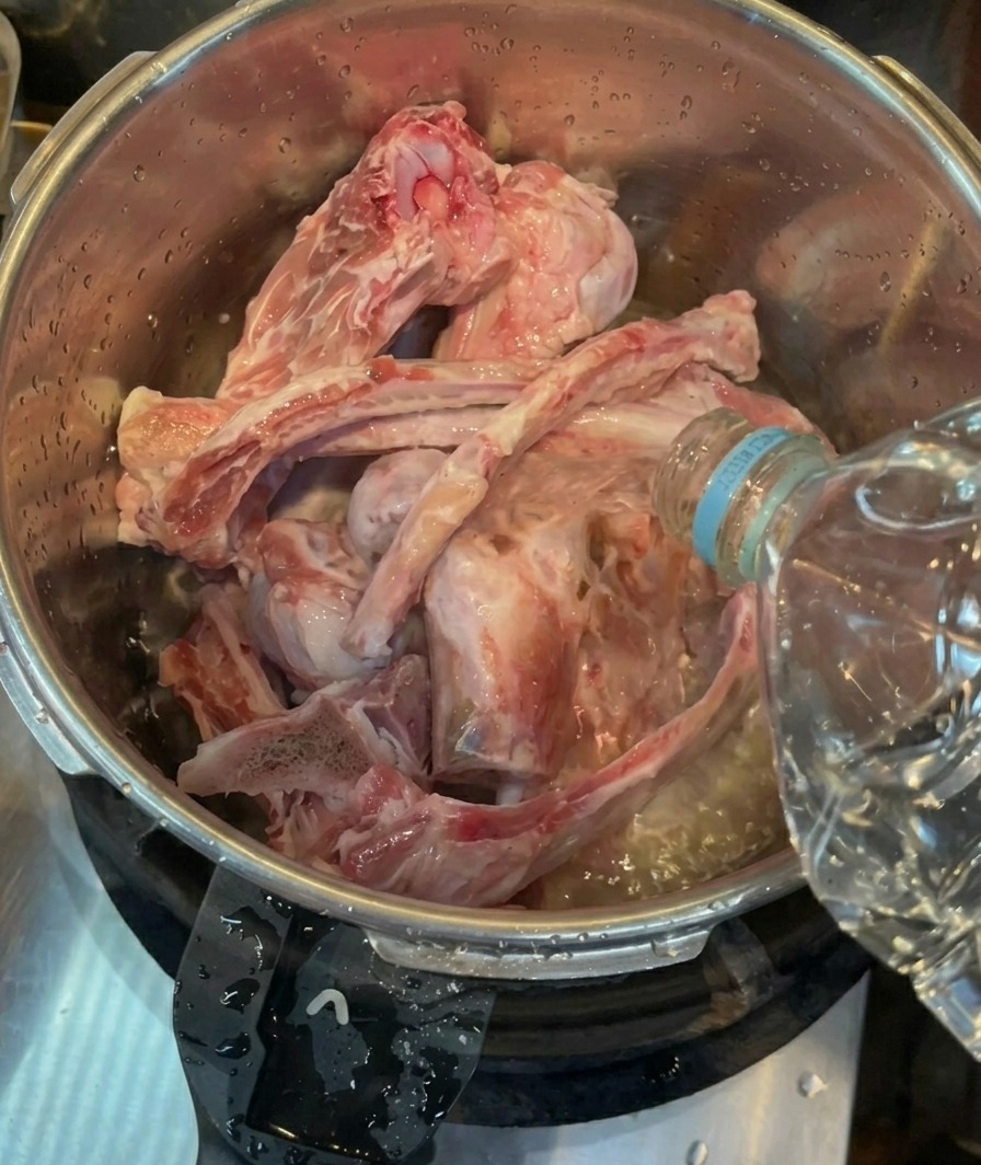 Stilles Wasser wird in einem Schnellkochtopf über gereinigte Schweineknochen gegossen.