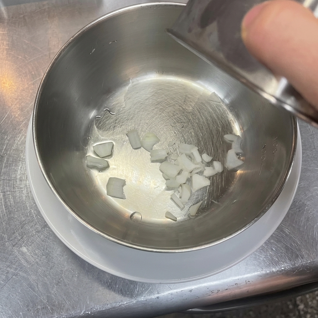Fein gewürfelte weiße Zwiebeln liegen am Boden einer Edelstahlschüssel.