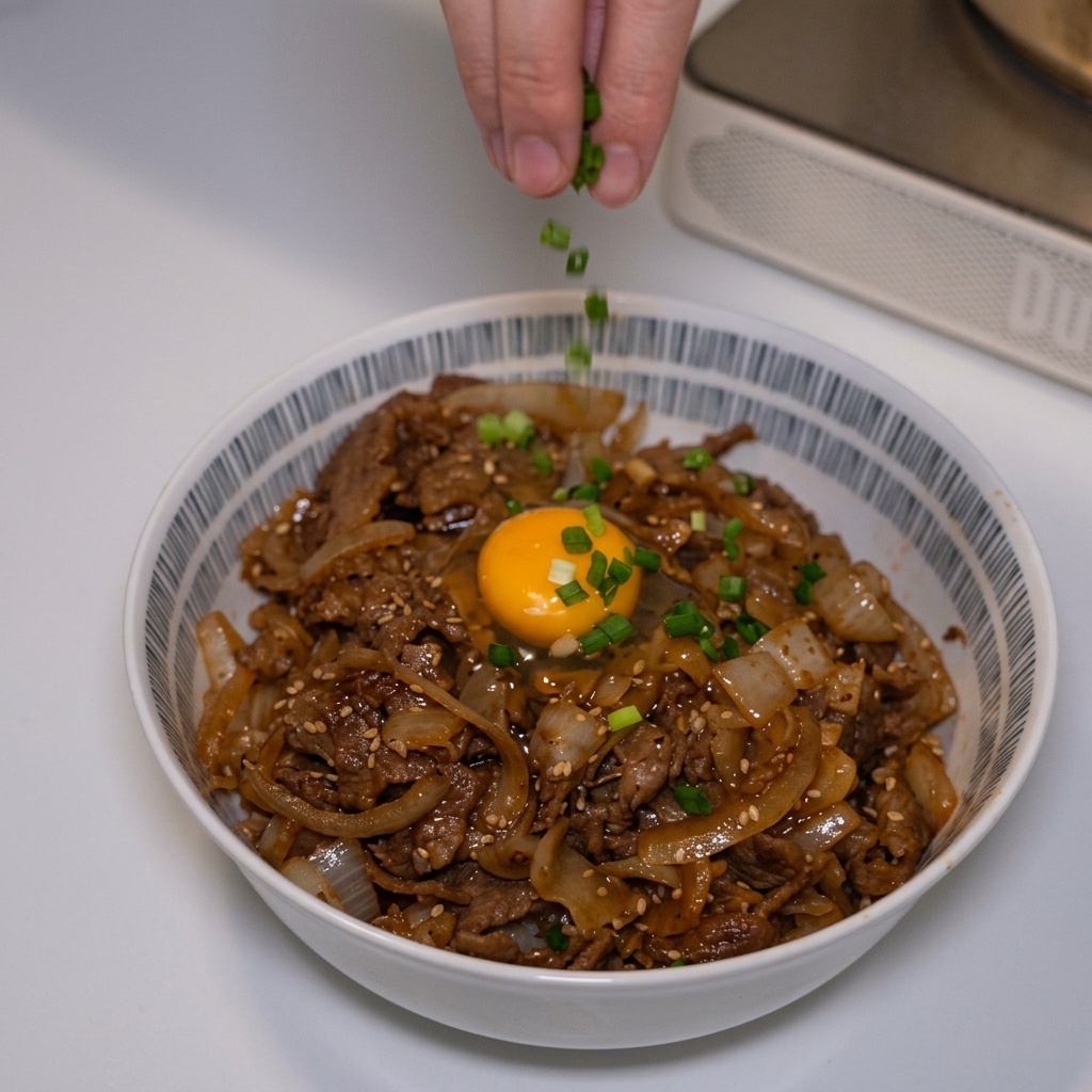 Frisch gehackte Frühlingszwiebeln werden über das fertige Gyudon mit Eigelb gestreut.