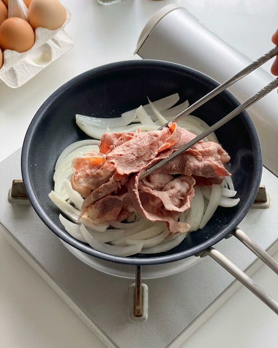 Metallstäbchen legen blanchierte Rindfleischscheiben auf die in der Pfanne garenden Zwiebeln.