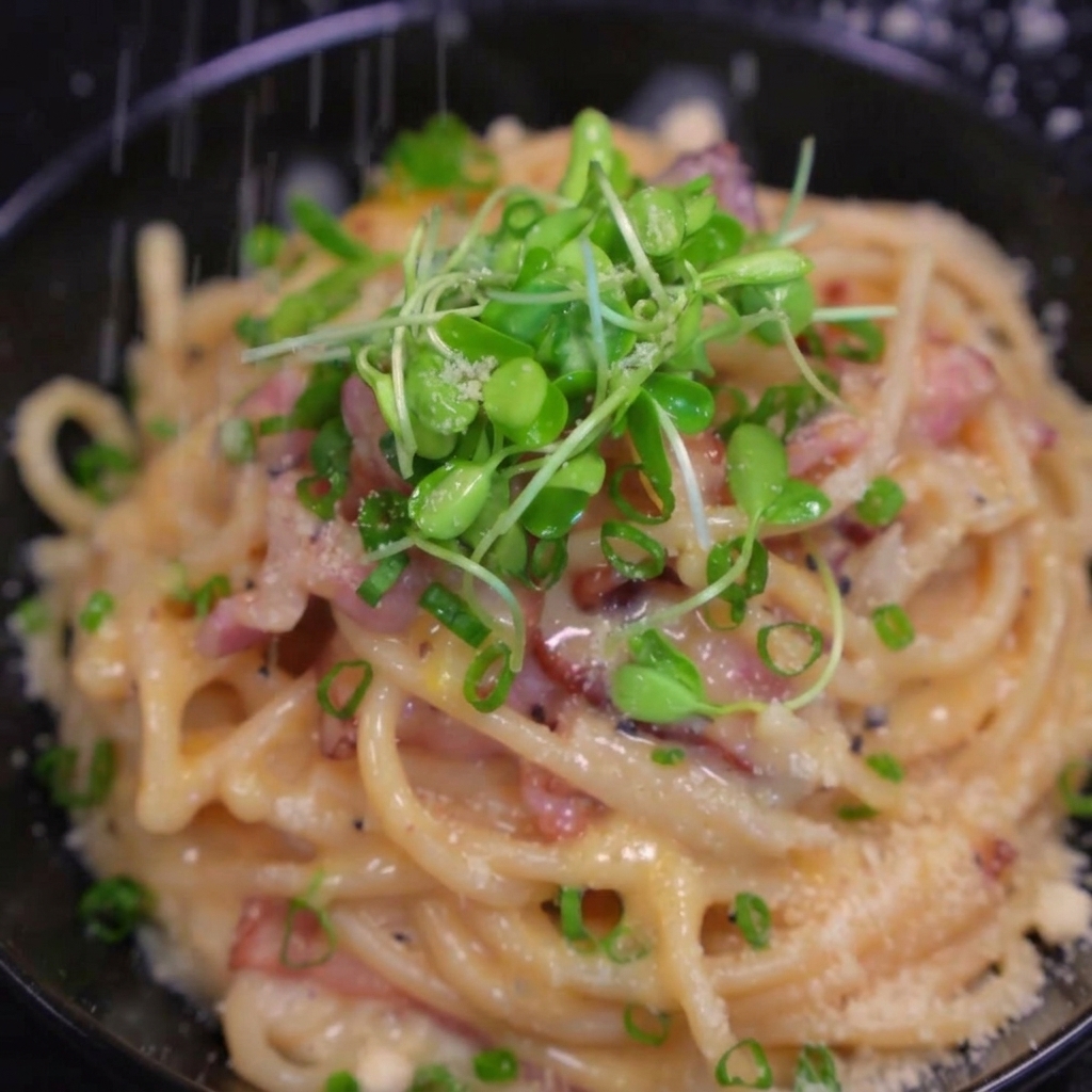 Frischer Käse wird über die fertige Pasta gerieben.
