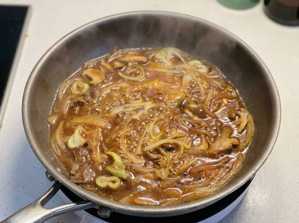 Verquirlte Eier werden kreisförmig in die Pfanne mit der köchelnden Sauce und den Zwiebeln gegossen.