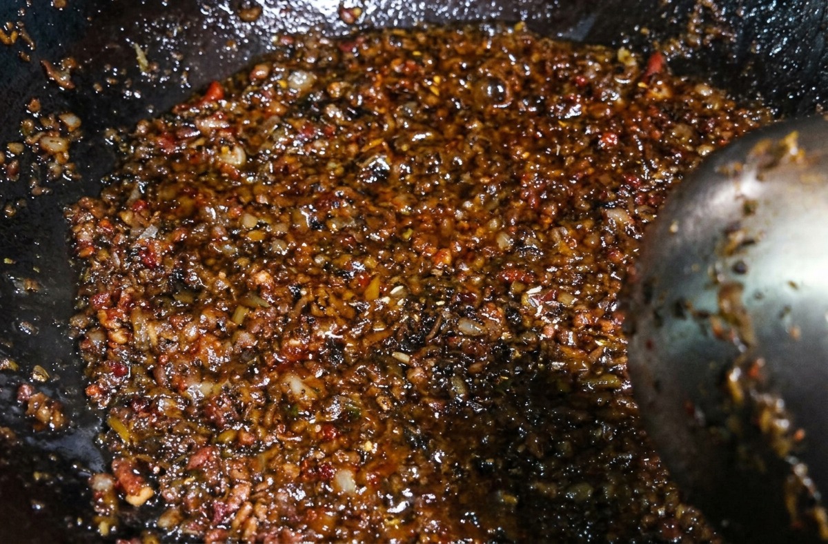 Die dunkle, herzhafte Mischung aus Hackfleisch und Gemüse wird nach dem Würzen im Wok umgerührt.