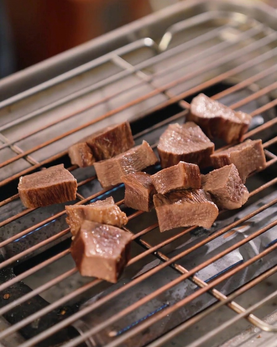 Mehrere dick geschnittene Stücke Rinderzunge auf einem Grillrost, glänzend überzogen mit einer dunklen Sauce.