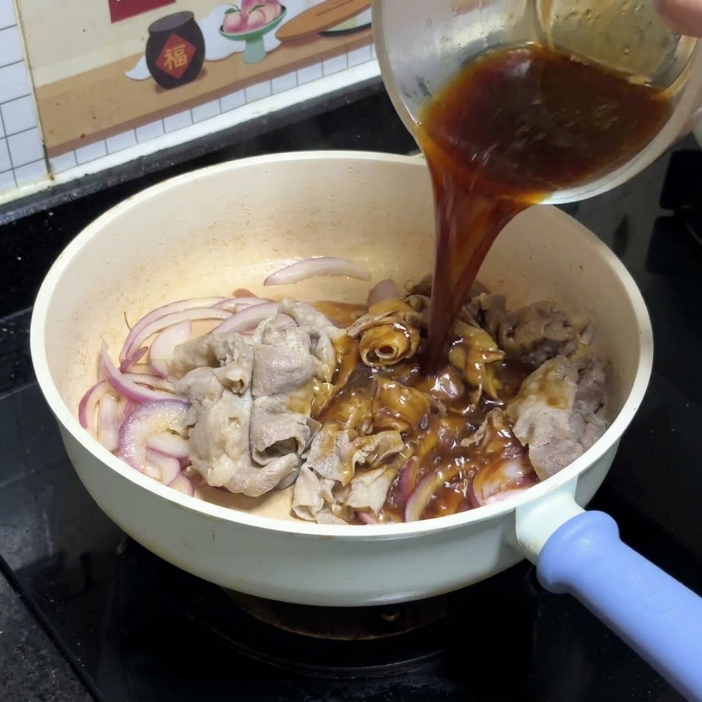 Dunkle Teriyaki-Sauce wird aus einer klaren Glasschüssel über die angebratenen roten Zwiebeln und Rindfleischscheiben in einer weißen Pfanne gegossen.