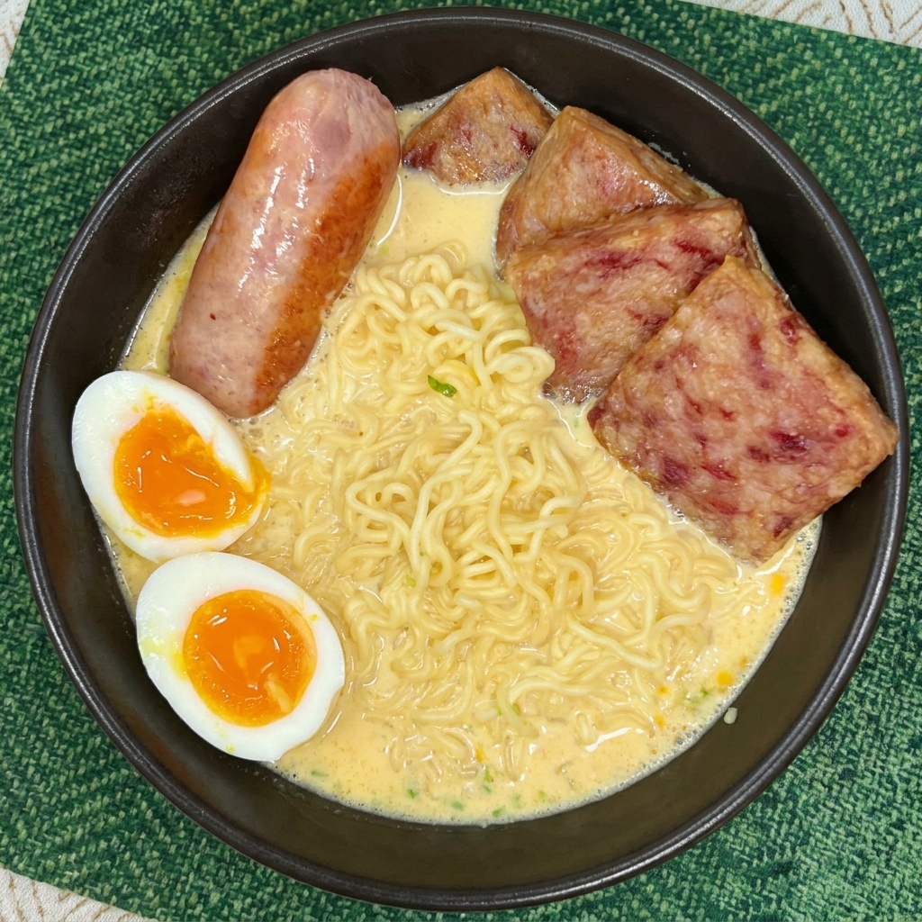 Eine Schüssel Ramen mit Spam, einem gegarten Würstchen und zwei Hälften eines weichgekochten Eies.