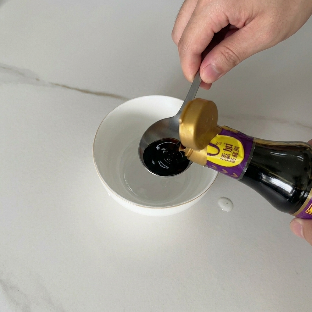 Dunkle Sojasauce wird aus einer Flasche in eine kleine weiße Keramikschüssel zu den anderen flüssigen Zutaten gegossen.