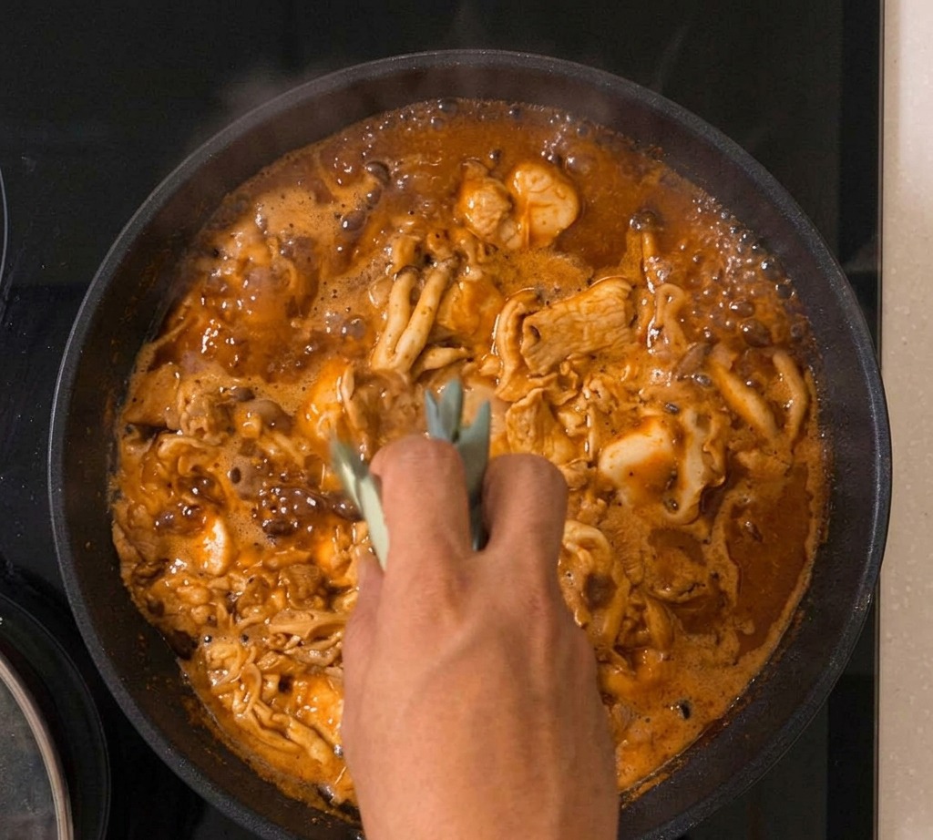 Das Oyakodon köchelt mit Frühlingszwiebeln zwischen dem stockenden Ei und dem Hähnchen in der Pfanne.