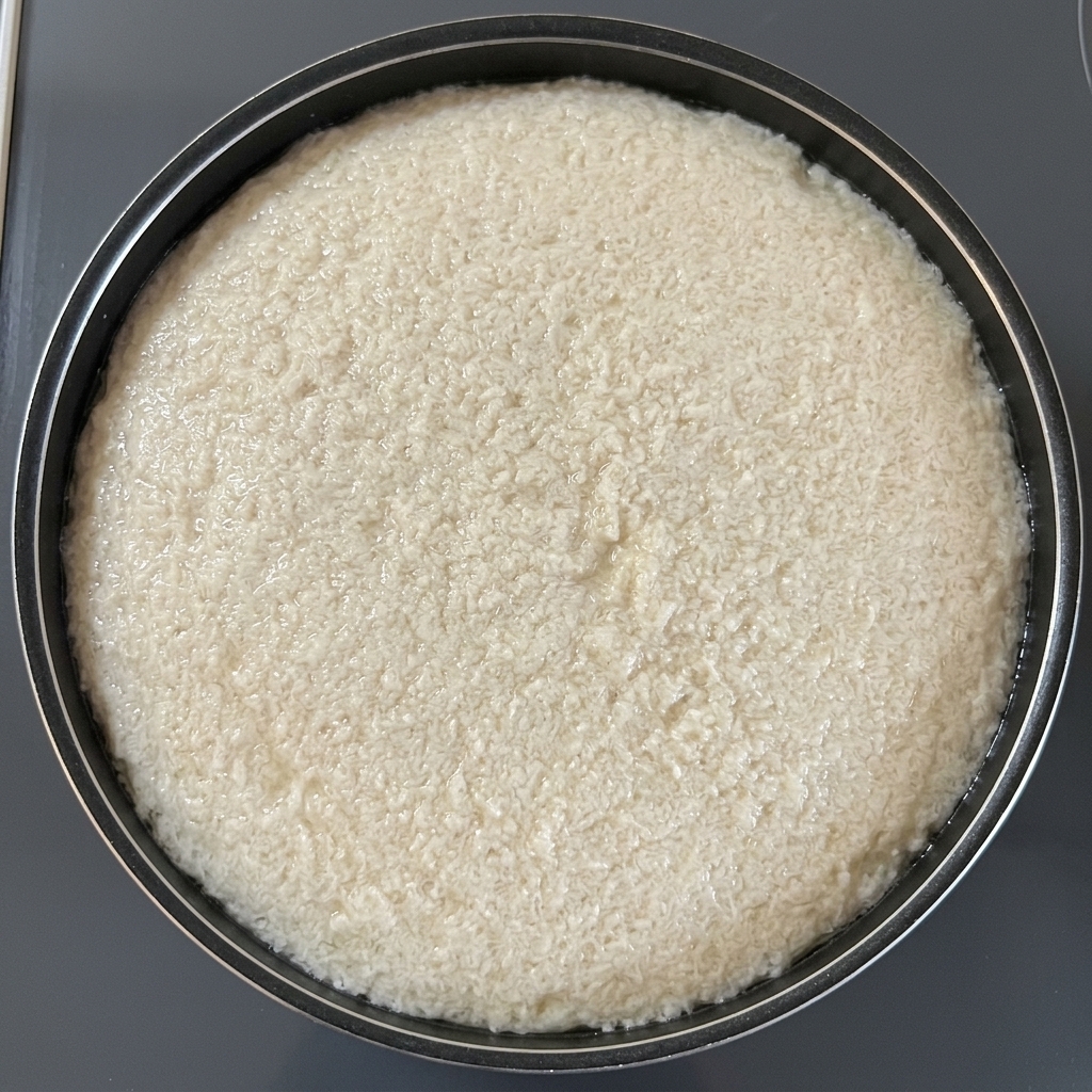 Ein rundes Stück Ölabsorptionspapier schwimmt auf kochendem Wasser in einem schwarzen Topf, um Schaum aufzusaugen.